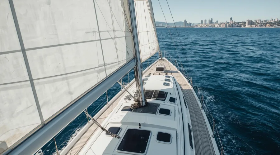 Vista desde la cubierta de un yate de vela navegando frente al skyline de Barcelona en un entorno corporativo exclusivo