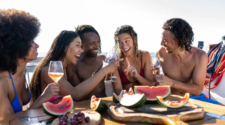 Familia joven brindando con vino rosado y comiendo fruta fresca en un barco en Barcelona