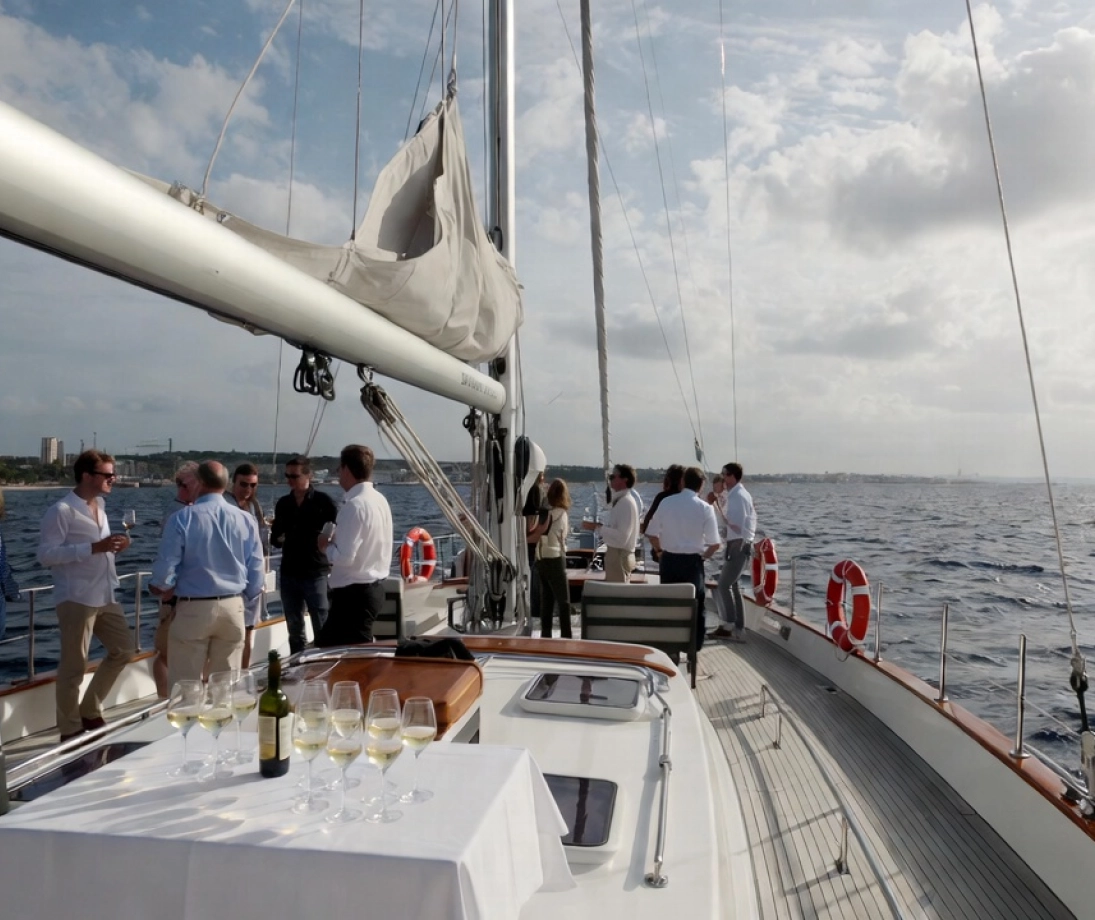 Grup de persones gaudint d'una sortida en veler de luxe navegant prop de la ciutat al capvespre