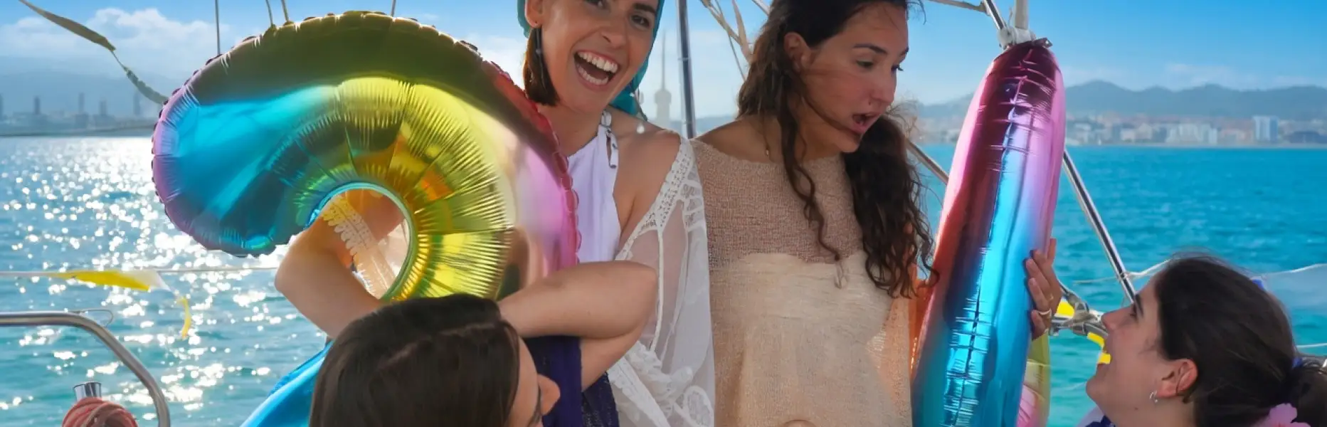 Kleine Freundinnengruppe, die eine Bootstour vor der Skyline von Barcelona mit bunten Luftballons genießt