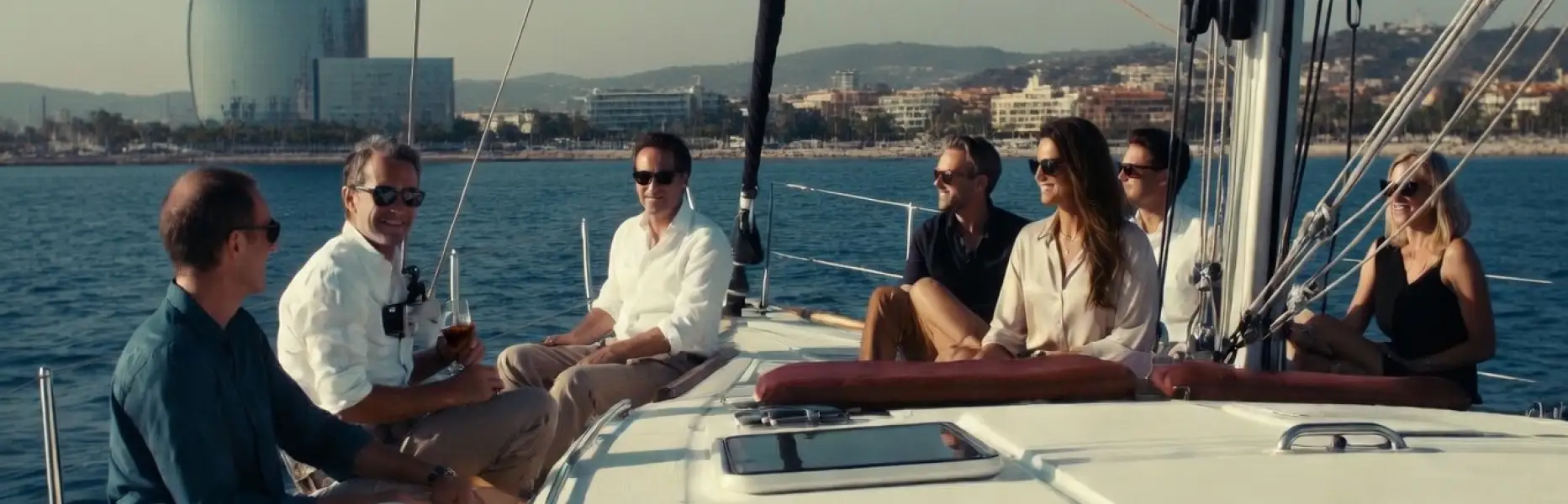 Gruppe von Freunden, die einen luxuriösen Segelcharter vor der Küste Barcelonas an einem sonnigen Tag genießt