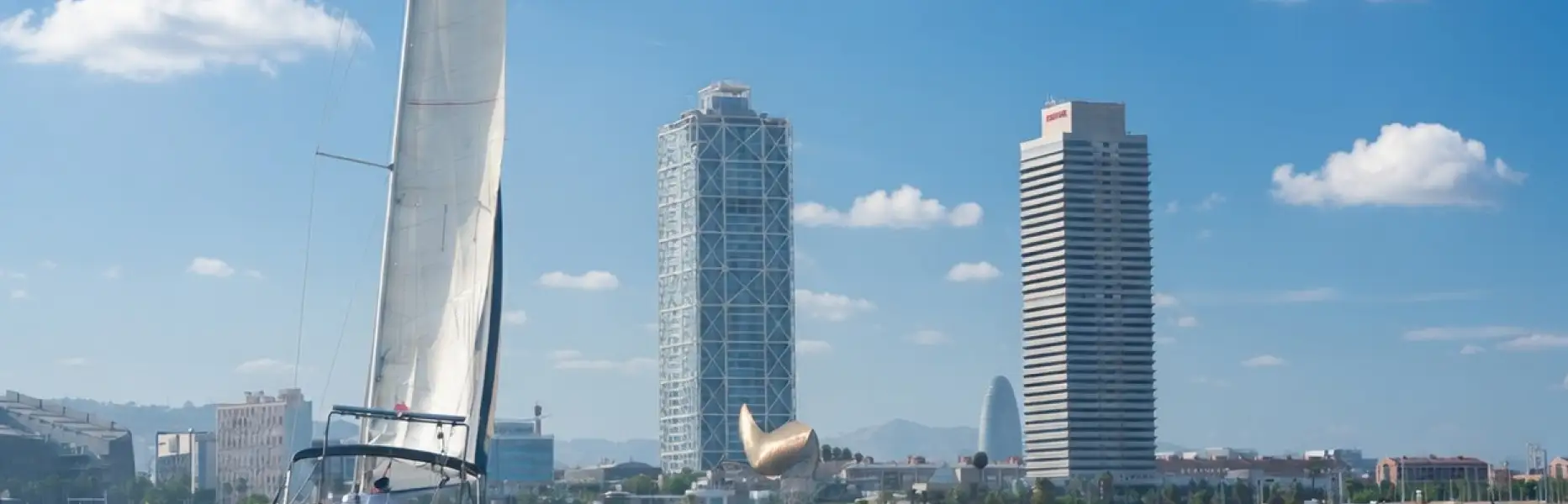 Veliero a noleggio che naviga in mare di fronte allo skyline di Barcellona in una giornata soleggiata