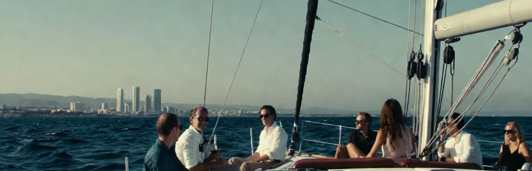 Group of people enjoying a luxury sailing yacht charter with city views in the background