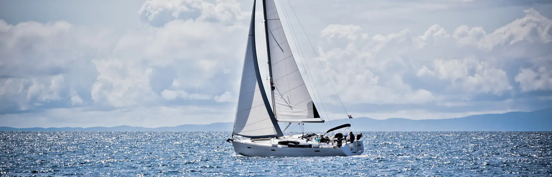 Barca a vela a noleggio che naviga in piccolo gruppo di fronte al Mar Mediterraneo in una giornata limpida