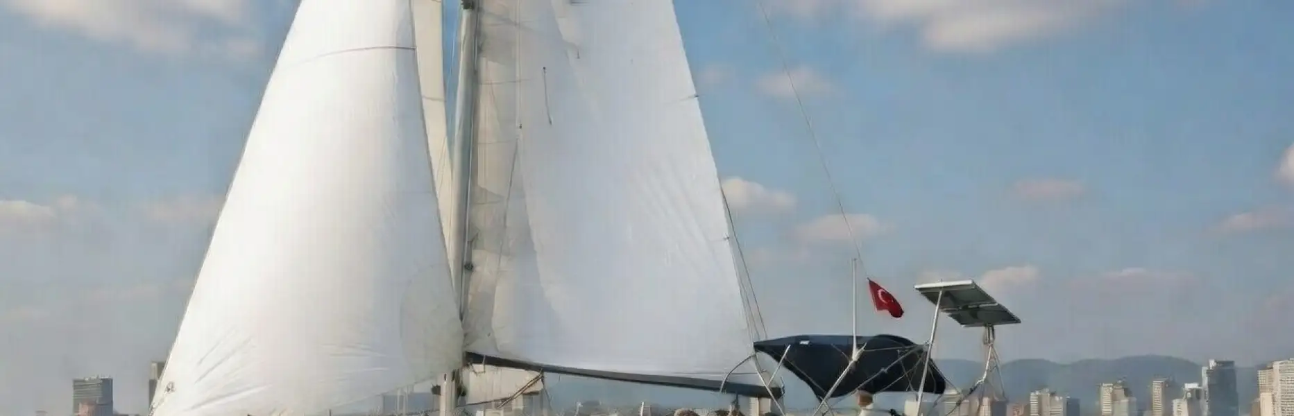 Voilier naviguant face au skyline de Barcelone par une journée ensoleillée avec une mer calme