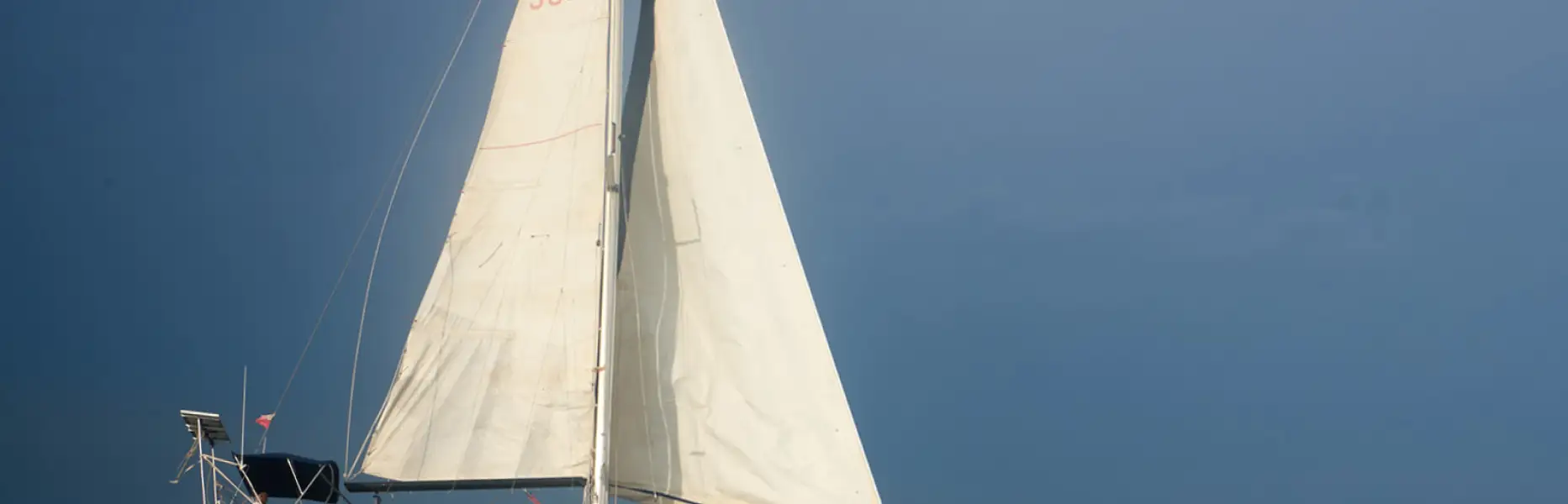 Velero de charter navegando a vela sobre un mar tranquilo bajo un cielo despejado