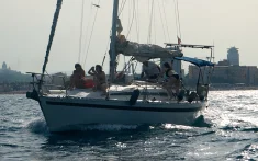 Grupo de personas disfrutando de un paseo en velero al atardecer frente a la costa de Barcelona