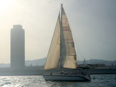 Velero de charter navegando frente al skyline de Barcelona