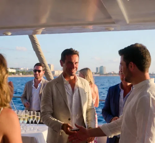 Group of people enjoying a luxury yacht charter event at sunset by the sea